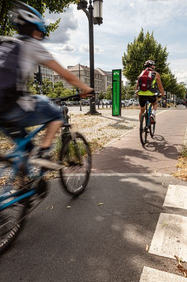 Fahrradbarometer in Berlin an der Straße des 17. Juni mit vorbeifahrenden Radfahrern