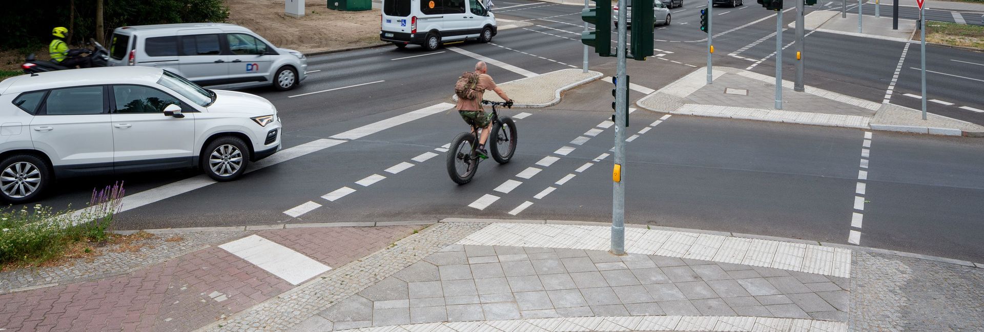 Fahrradfahrer fährt auf einem Radweg über eine große Kreuzung