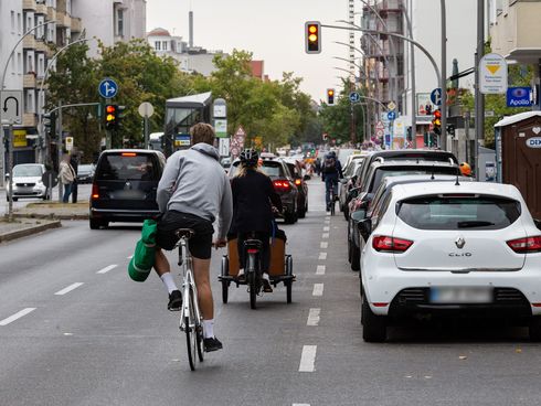 Fahrradfahrer fahren auf der Grunewaldstraße auf eine Kreuzung zu. Rechts von ihnen parken Autos.