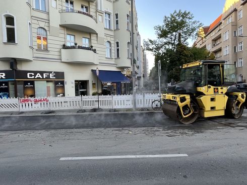 Baumaschine bearbeitet Asphalt auf einer Straße.