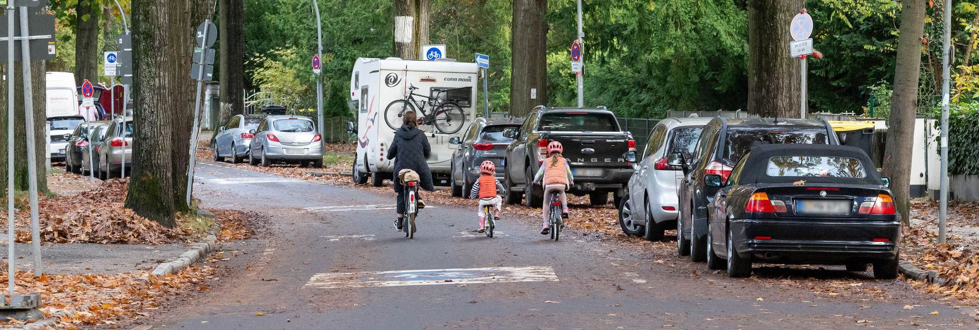 Zu sehen sind eine Frau und zwei Kinder auf Fahrrädern, die auf einer Fahrradstraße fahren.