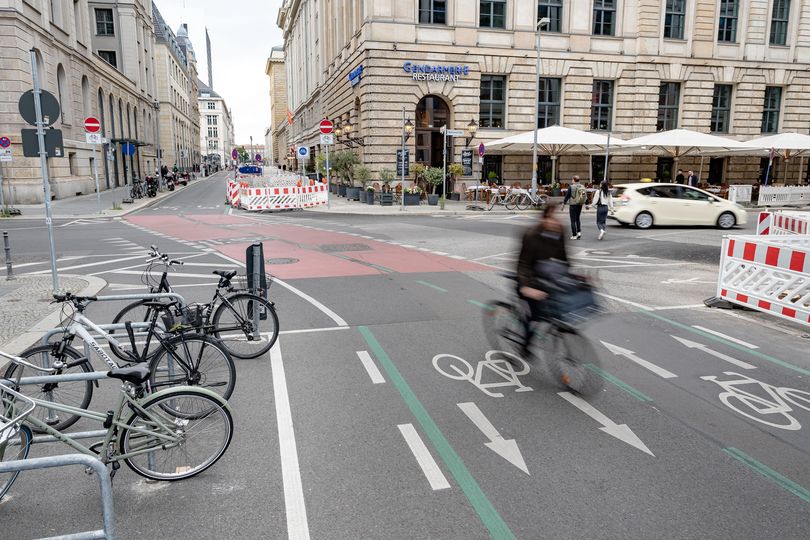 Radfahrende fährt entlang der markierten Fahrradstraße mit Rotbesichtung. Am Rand sind Kreuzberger Bügel als Fahrradabstellanlagen aufgestellt.