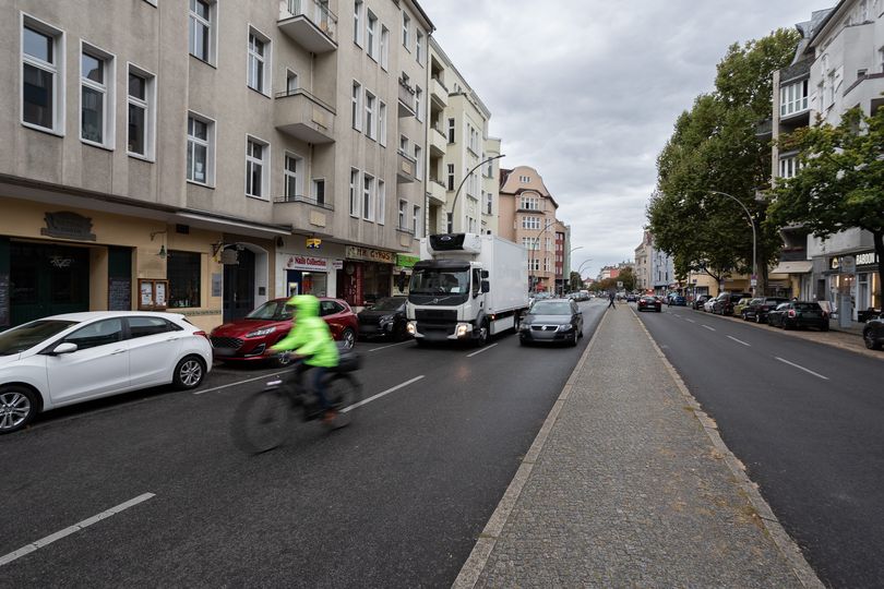 Vorher-Bild: Auf der Grunewaldstraße hält ein LKW in zweiter Reihe. Weitere Autos und Radfahrer sind auf der Fahrbahn unterwegs.