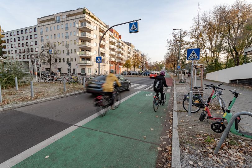 grün und rot markierter Radfahrstreifen mit Radfahrenden vor einem Zebrastreifen